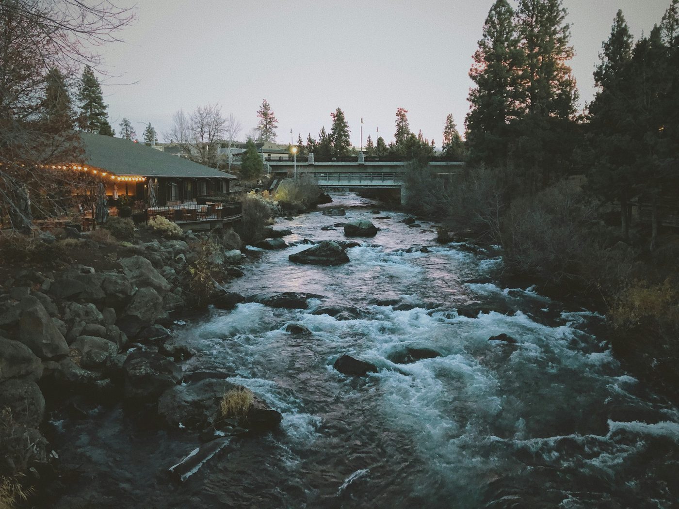 Black and white river scene in Bend with a bridge and homes along the water